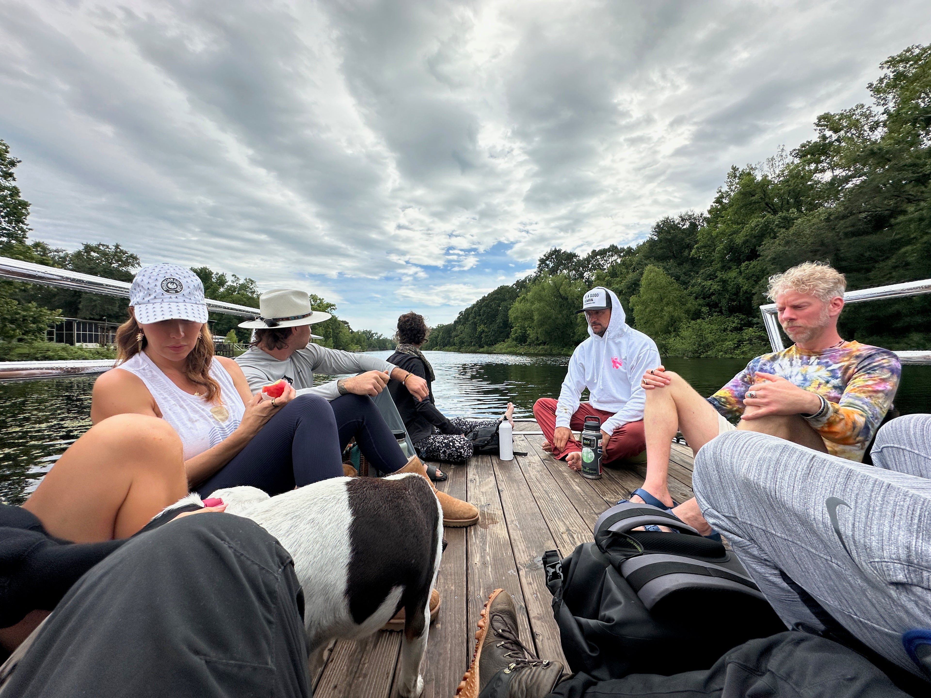 Group of people relaxing on a wooden dock surrounded by nature, sharing moments of mindfulness and connection during a community retreat.