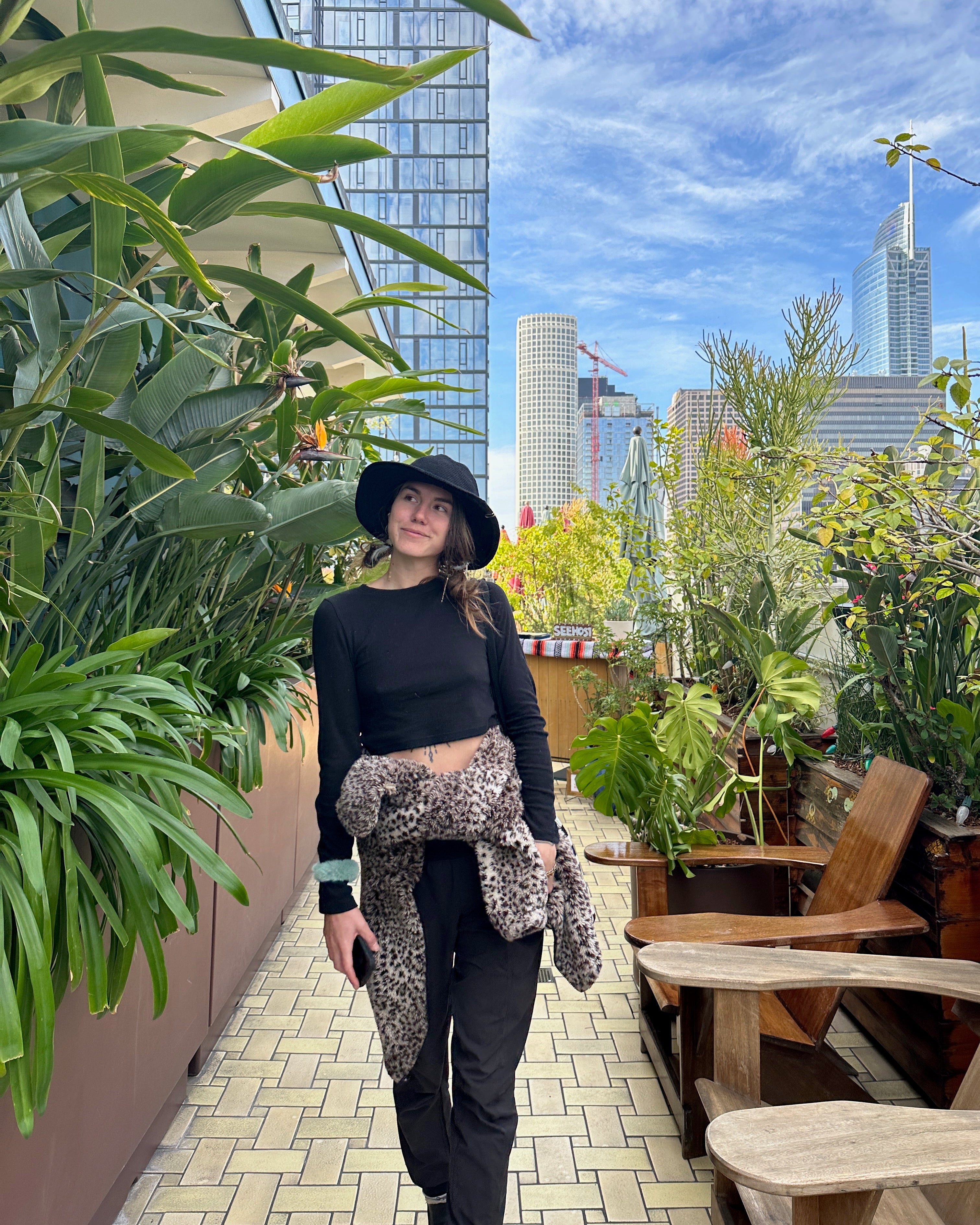 Headshot of Chamomile Diddell on a rooftop garden with urban skyscrapers in the background.