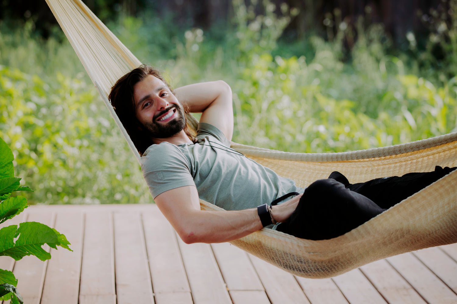 Person smiling and relaxing in a hammock outdoors, surrounded by greenery, symbolizing mindfulness, relaxation, and the peaceful lifestyle associated with the Microdose Journal.