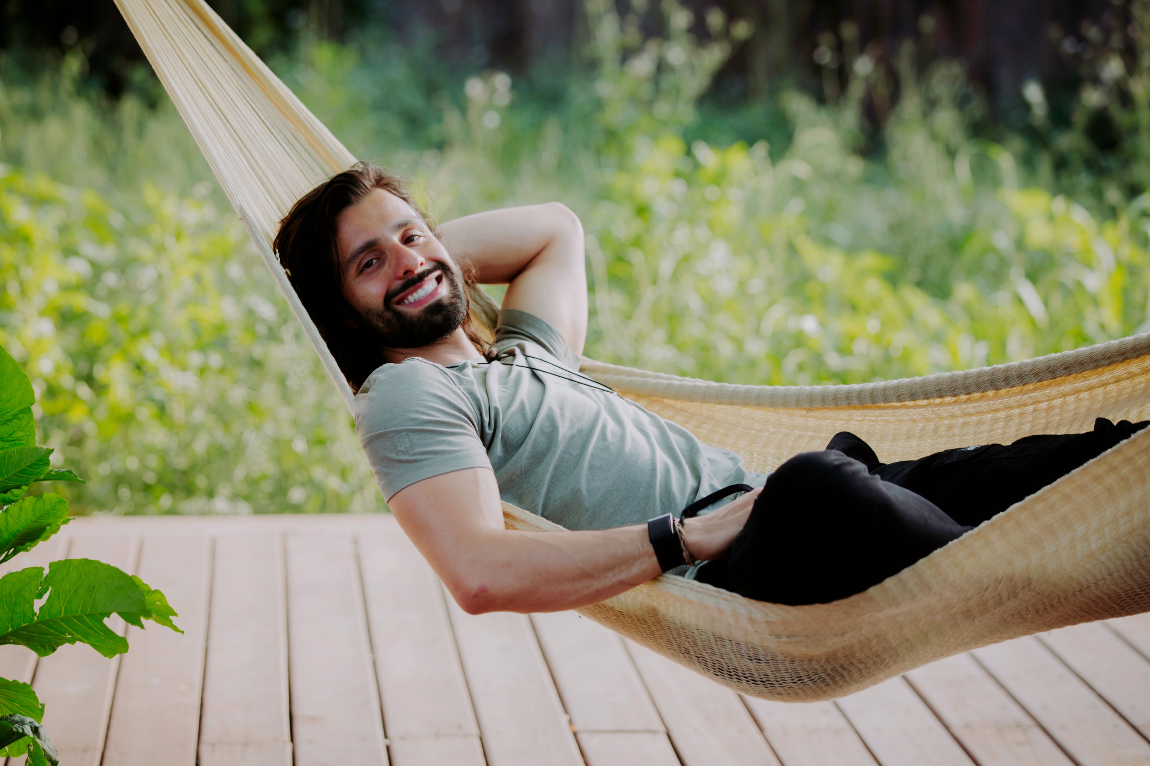 Person smiling and relaxing in a hammock outdoors, surrounded by greenery, symbolizing mindfulness, relaxation, and the peaceful lifestyle associated with the Microdose Journal.