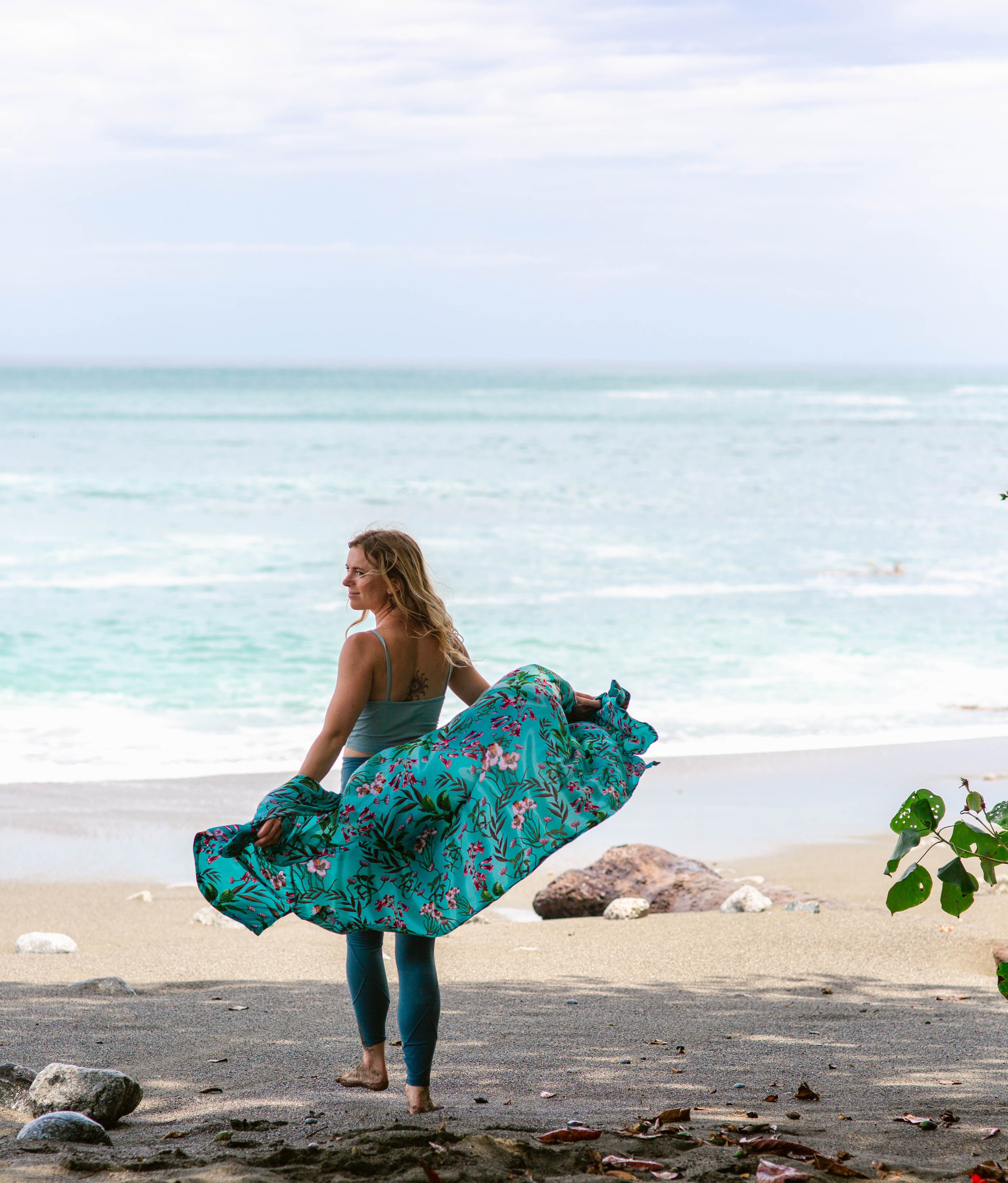 Steph Nally, yoga and meditation instructor, walking barefoot by the beach with a flowing colorful shawl, embracing mindfulness, nature, and serenity.